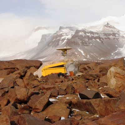A GPS antenna on a rocky slope on the side of a mountain in Antarctica.