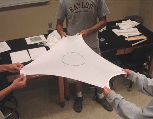 Baylor University students tug a tee-shirt to see how the circle changes shape as they strain it. Credit: Cronin, 2013.