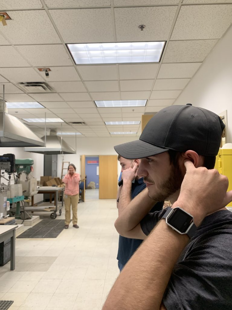 Geo-Launchpad intern Jimmy Swift plugging his ears while an employee cuts a sample of granite.