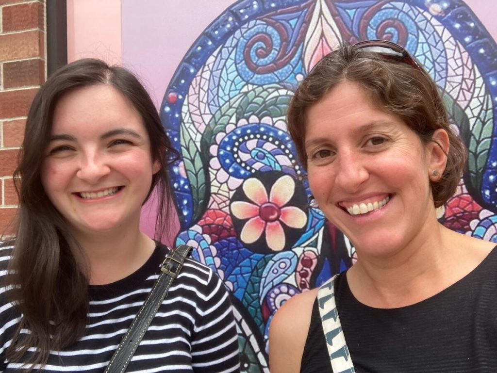 Samantha Motz and Dr. Kamini Singha smiling in front of a mural.