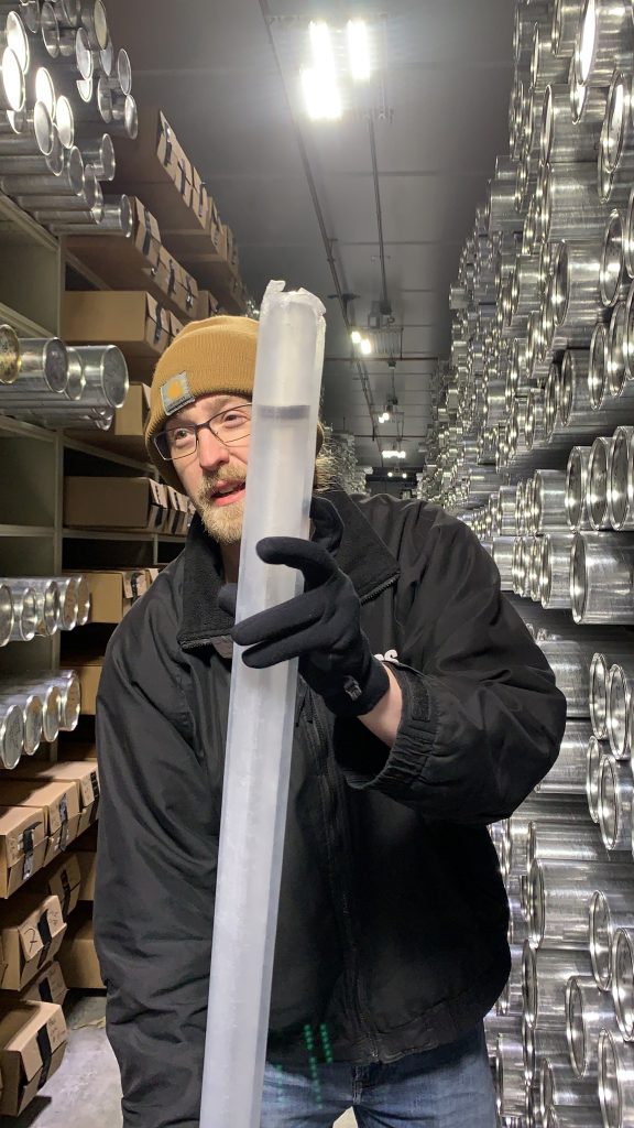 Richard Nunn holding up an ice core with a gray segment that indicates there was a volcanic eruption.