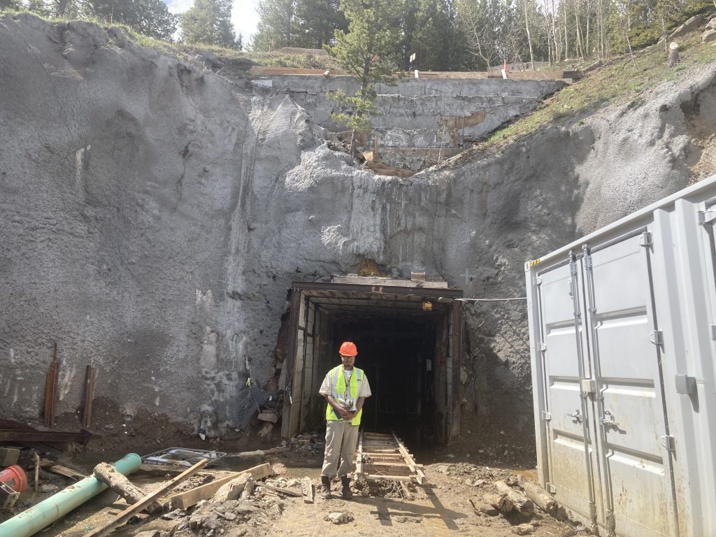 RESESS intern Shams Ahmed standing in front of a mine shaft at the Cross Mine, wearing a safety vest and hard hat.