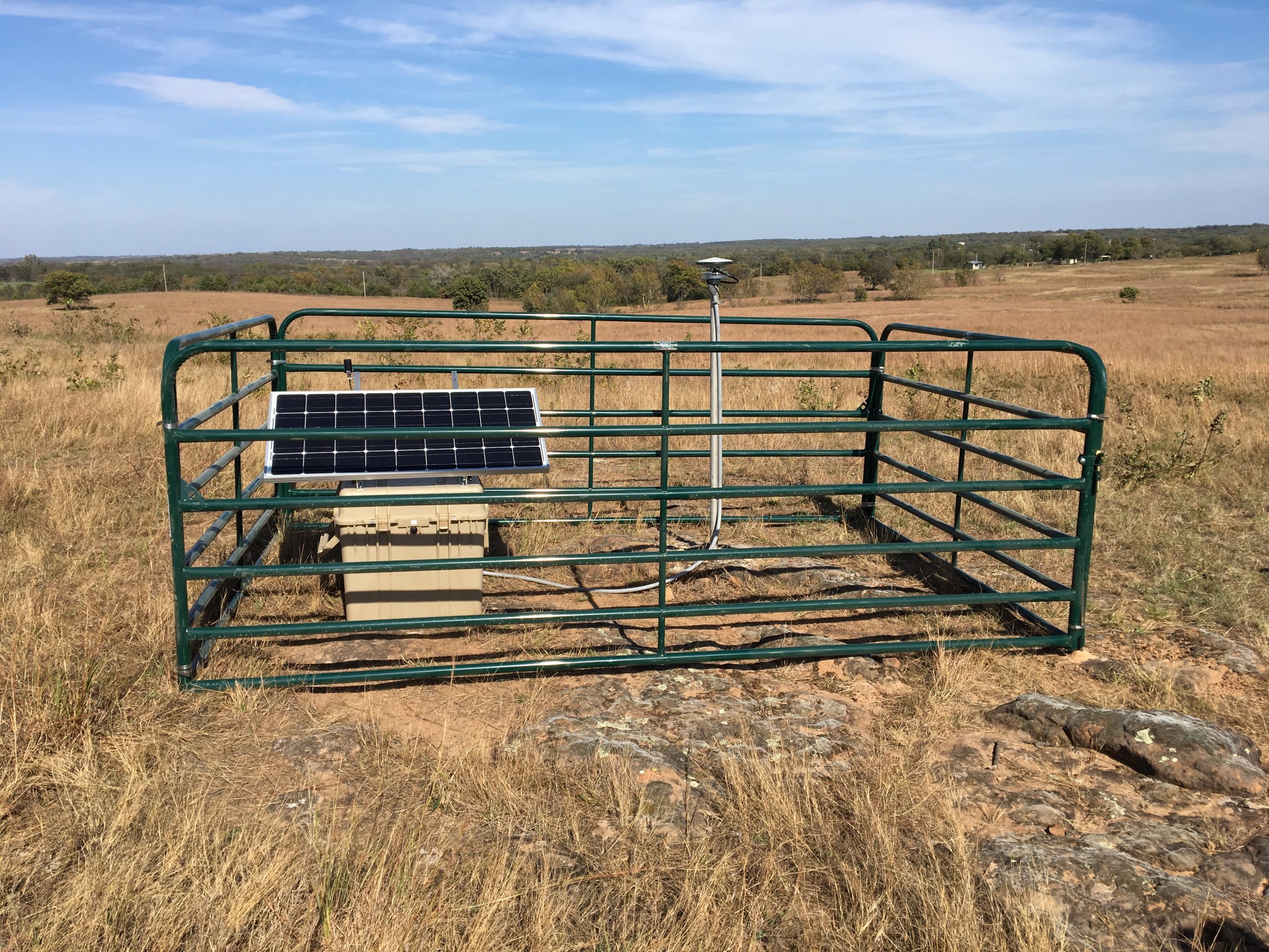 GPS monument and solar panel in a fenced area.
