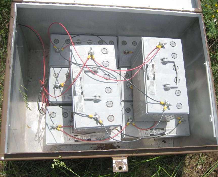 enclosure in the ground open with batteries and wiring visible