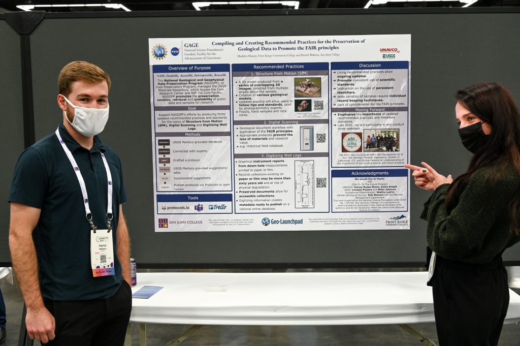 two interns stand in front of conference poster