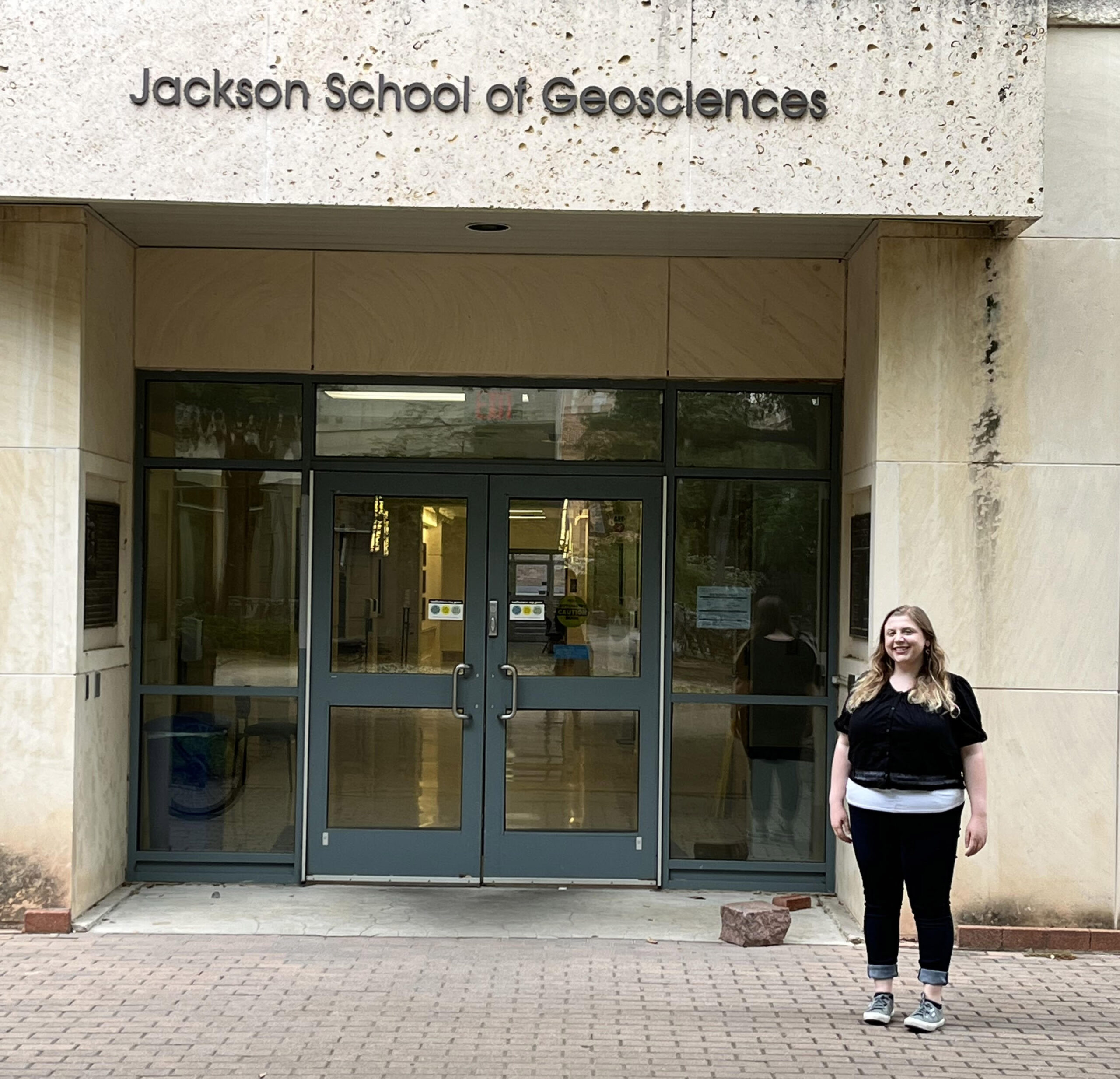 photo of woman standing in front of building labeled Jackson School of Geosciences