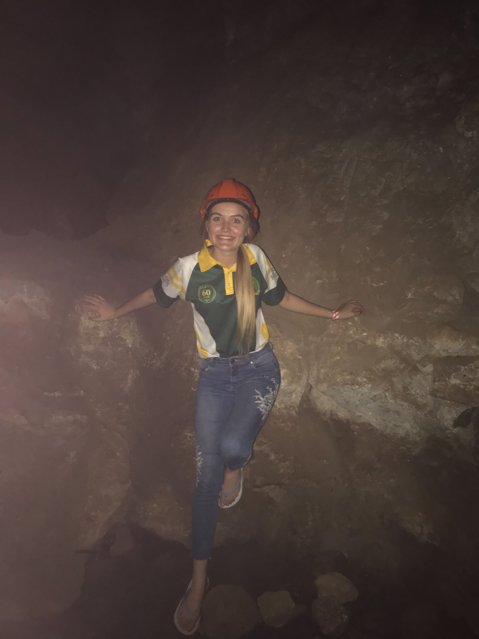 RESESS Satellite Intern Courteney Pike smiles in the Sterkfontein Caves, wearing a hard hat.