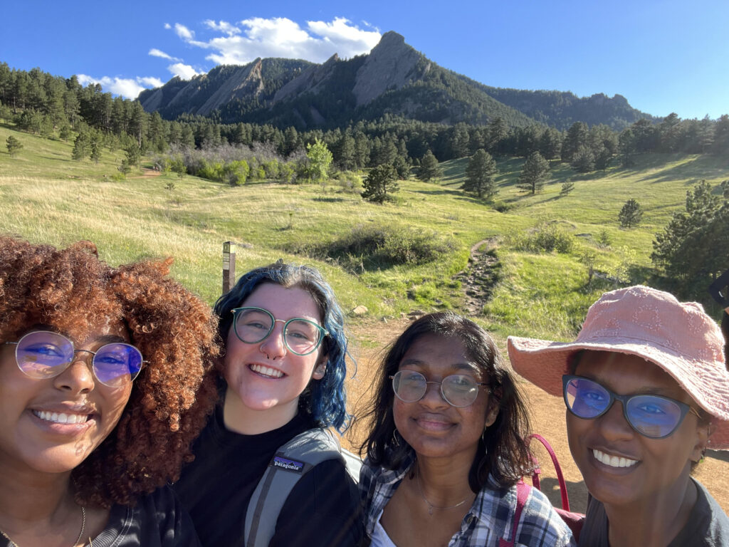 Selfie of 2022 interns (L to R): Keneni Godana (RESESS), Addison Curtis (RESESS), Shradha Ravikumar (RESESS), and Kayla Byrd (USIP) smiling in front of the Flatirons in Boulder, CO.