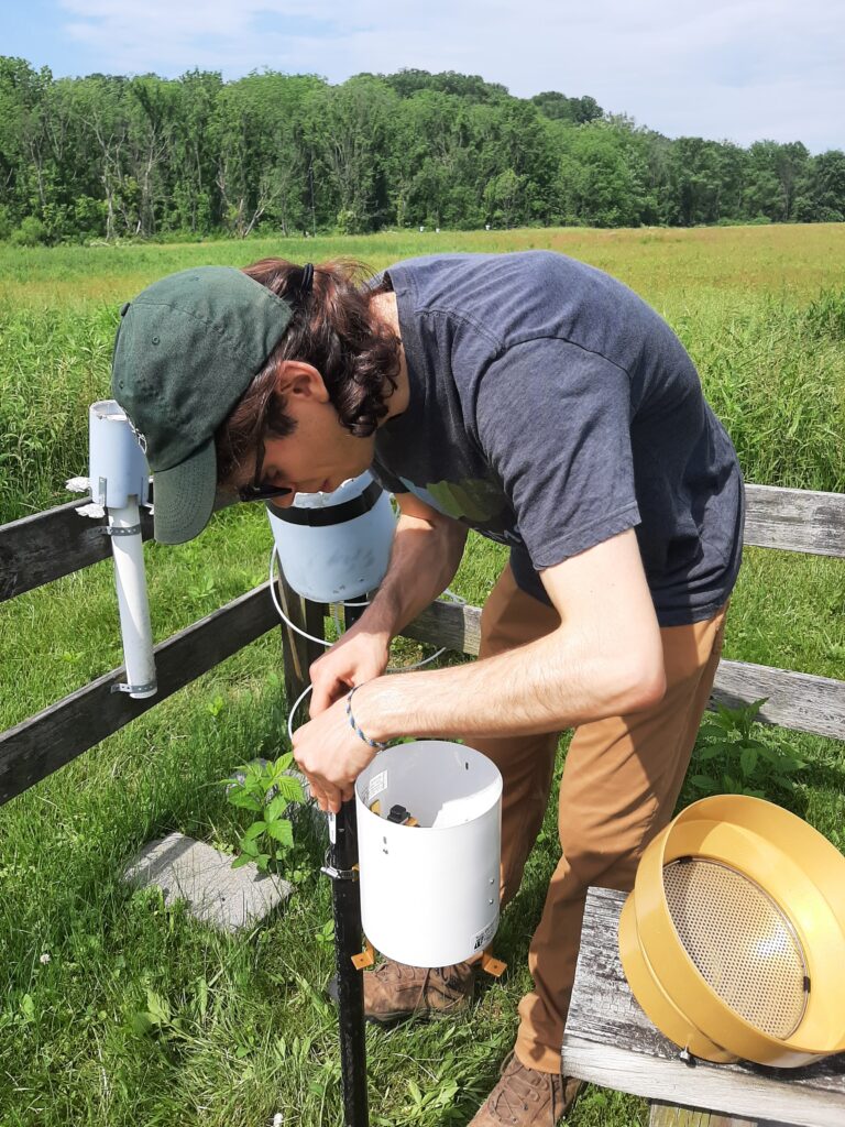 David Litwin is bent over to work on the wiring for the installation of a rain gauge.