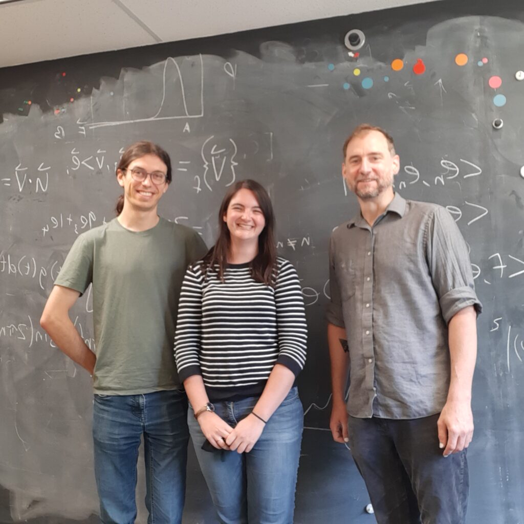 RESESS intern Samantha Motz (middle) with her mentors, JHU graduate student David Litwin (left) and Dr. Ciaran Harman (right) in front of a blackboard with linear algebra equations written in chalk.