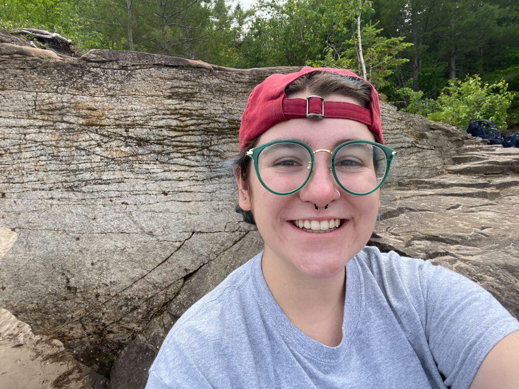 Selfie of RESESS intern Addison Curtis with bed of rock behind them in the Upper Peninsula of Michigan.